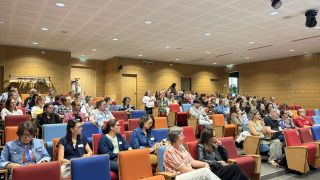 Personnes installées dans un amphithéâtre pour une conférence.